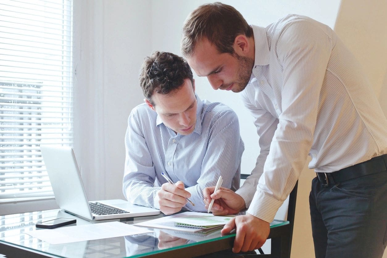 Two men are working together on paperwork.