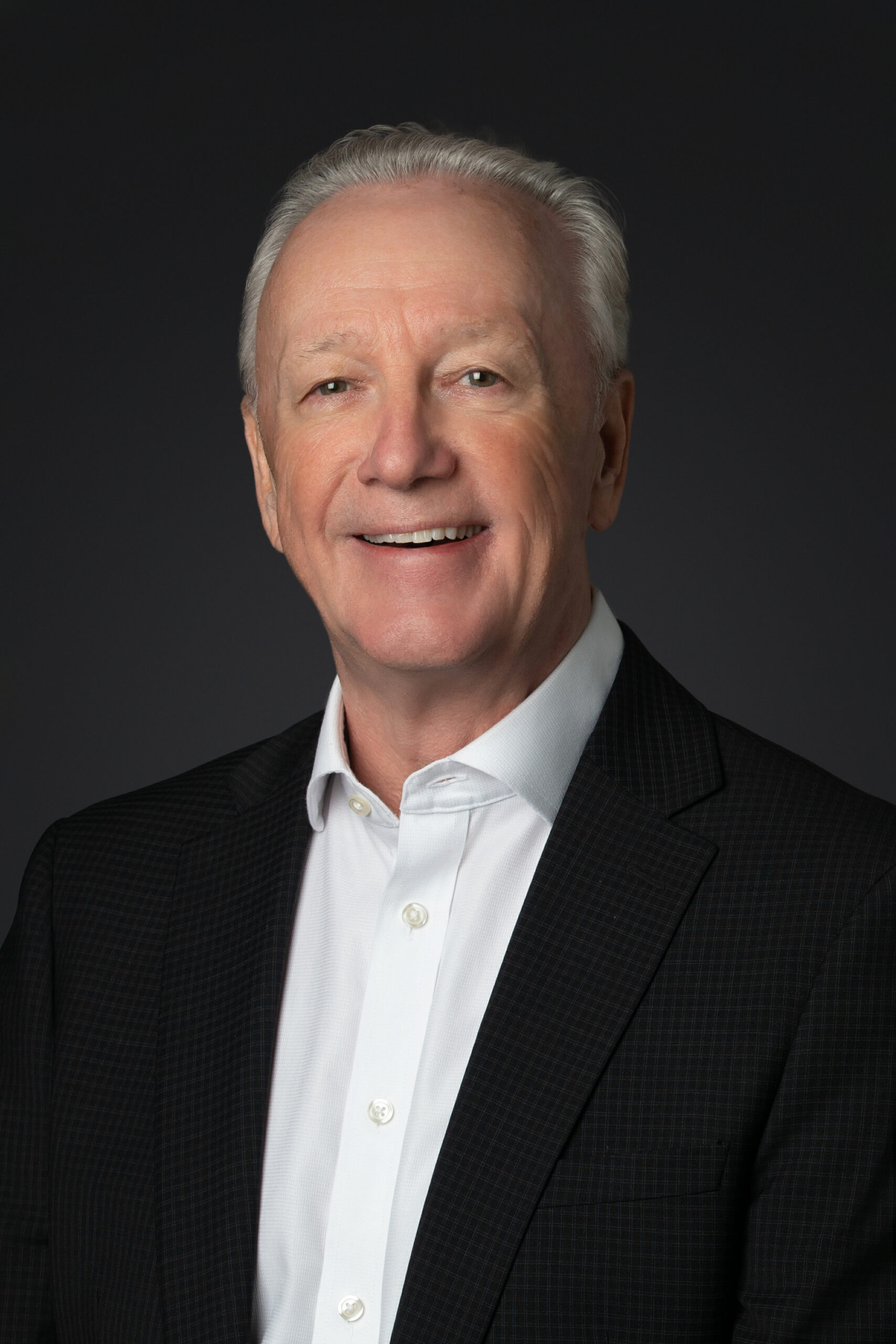 A man in a suit and tie smiling for the camera.