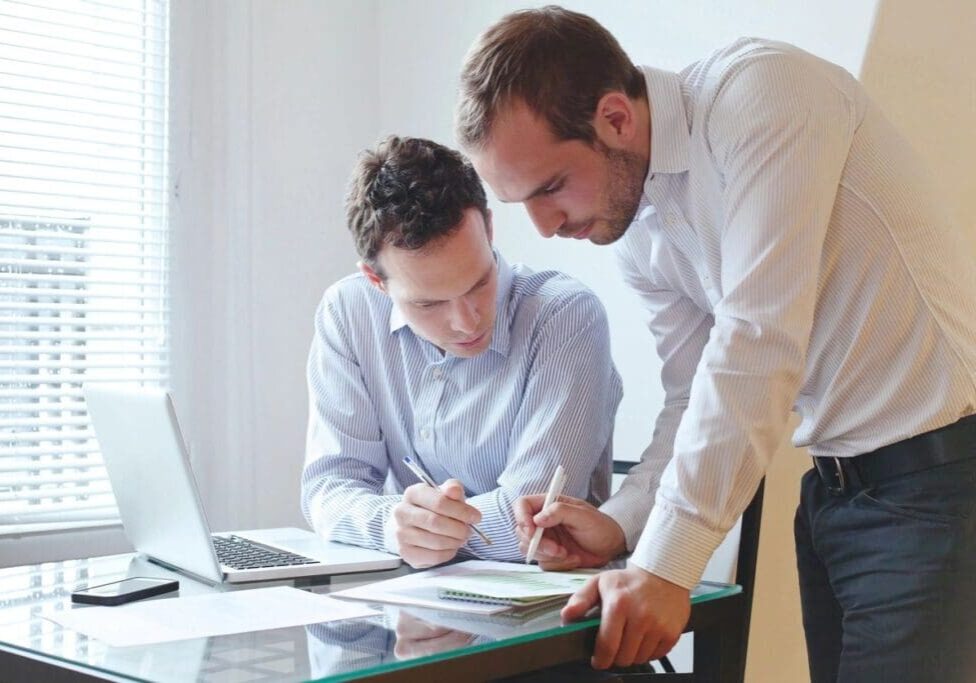 Two men are working together on paperwork.